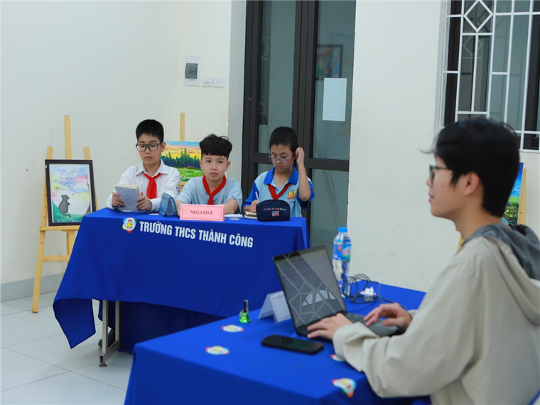 A group of kids sitting at a table with a computer

Description automatically generated