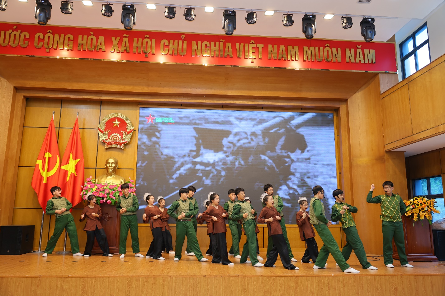 A group of people in green uniforms on a stage

Description automatically generated